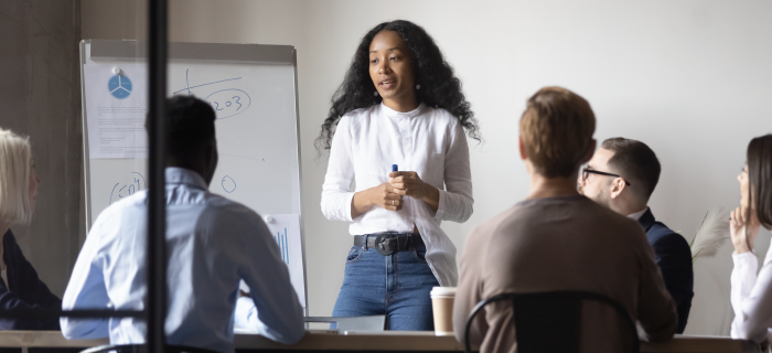 A woman standing in front of her team presenting.