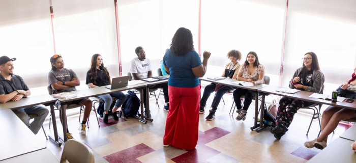 A teacher standing in front of her students, all of the students are smiling